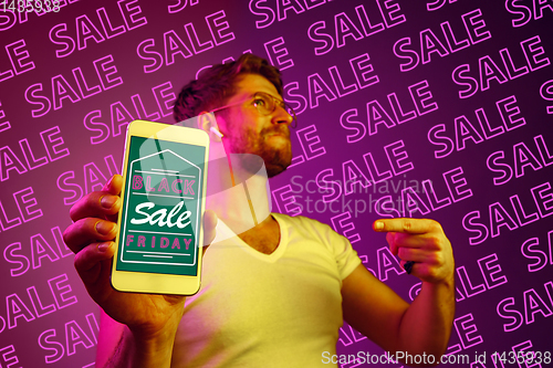 Image of Portrait of man showing screen of mobile phone, black friday