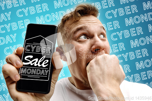 Image of Portrait of man showing screen of mobile phone, black friday