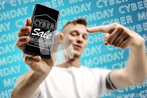 Image of Portrait of man showing screen of mobile phone, black friday