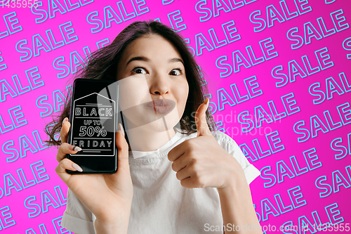 Image of Portrait of woman showing screen of mobile phone, black friday