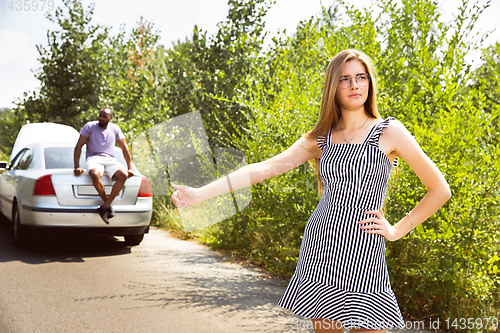 Image of Young multiethnic international couple traveling on the car in sunny day