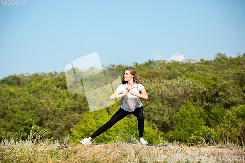 Image of Beautiful young woman training flexibility outdoors