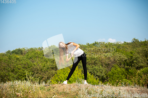 Image of Beautiful young woman training flexibility outdoors