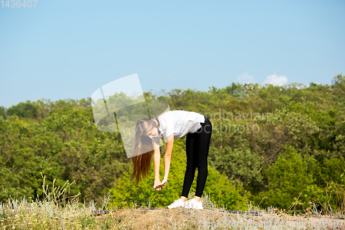 Image of Beautiful young woman training flexibility outdoors