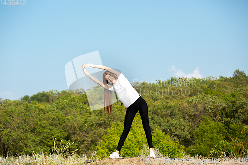 Image of Beautiful young woman training flexibility outdoors
