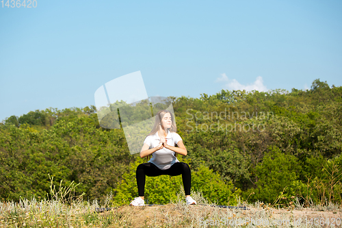 Image of Beautiful young woman training flexibility outdoors