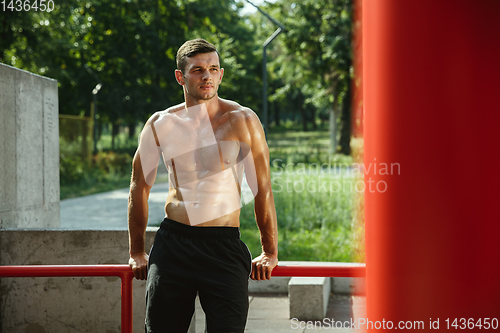 Image of Young muscular man while doing his workout outside at playground