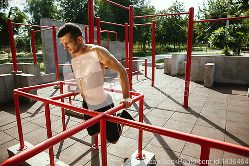 Image of Young muscular man while doing his workout outside at playground