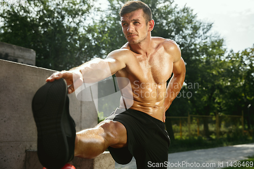 Image of Young muscular man while doing his workout outside at playground