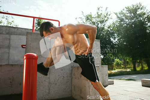 Image of Young muscular man while doing his workout outside at playground