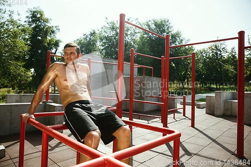 Image of Young muscular man while doing his workout outside at playground