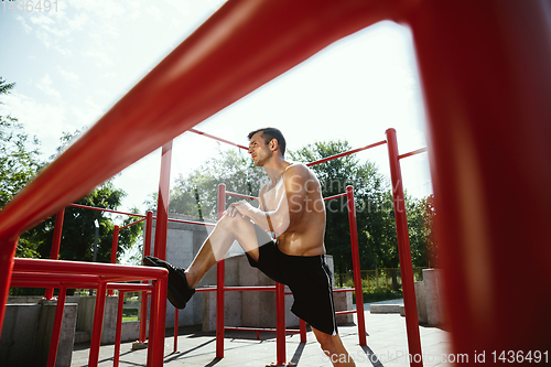 Image of Young muscular man while doing his workout outside at playground