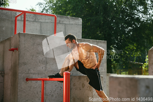 Image of Young muscular man while doing his workout outside at playground