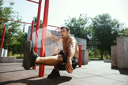 Image of Young muscular man while doing his workout outside at playground