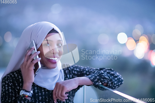 Image of Young Muslim woman on  street at night using phone