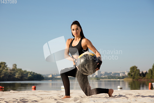 Image of Young healthy female athlete doing workout at the beach