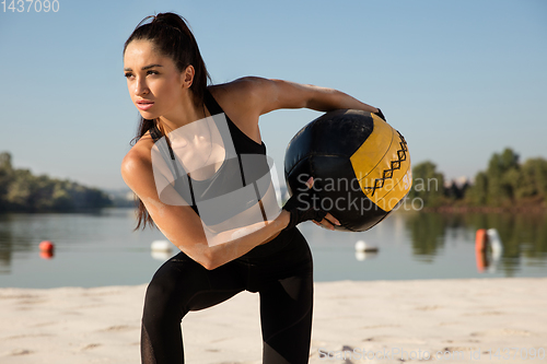 Image of Young healthy female athlete doing workout at the beach