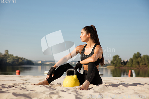 Image of Young healthy female athlete doing workout at the beach