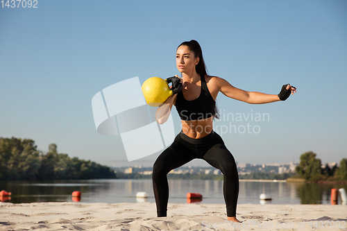 Image of Young healthy female athlete doing workout at the beach