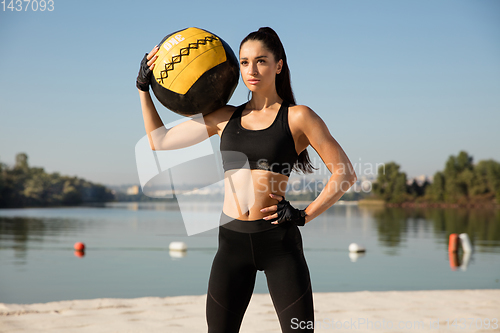 Image of Young healthy female athlete doing workout at the beach
