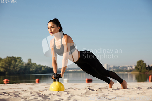 Image of Young healthy female athlete doing workout at the beach