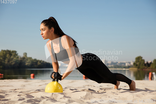 Image of Young healthy female athlete doing workout at the beach