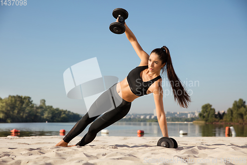 Image of Young healthy female athlete doing workout at the beach