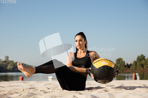 Image of Young healthy female athlete doing workout at the beach