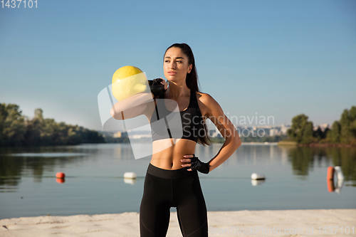 Image of Young healthy female athlete doing workout at the beach