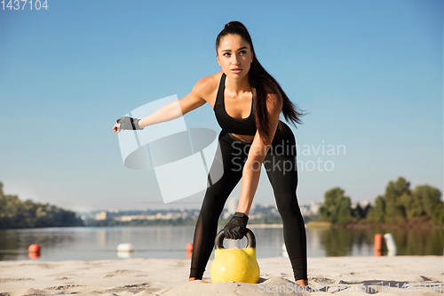 Image of Young healthy female athlete doing workout at the beach