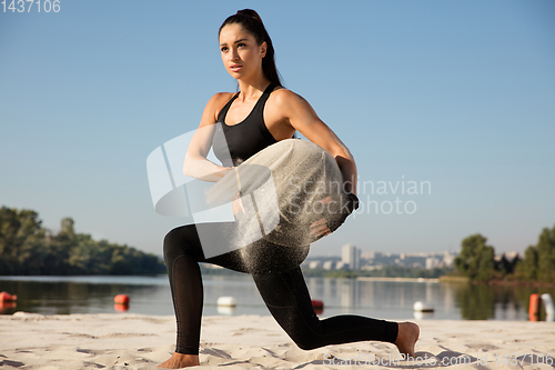 Image of Young healthy female athlete doing workout at the beach