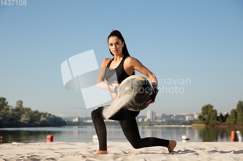 Image of Young healthy female athlete doing workout at the beach