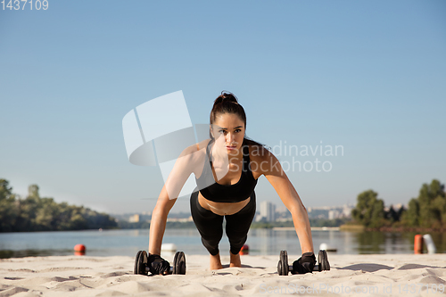 Image of Young healthy female athlete doing workout at the beach