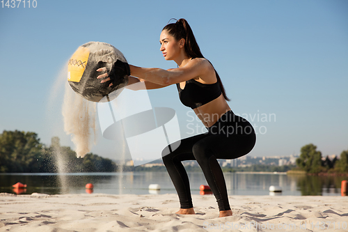 Image of Young healthy female athlete doing workout at the beach
