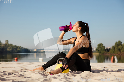 Image of Young healthy female athlete doing workout at the beach