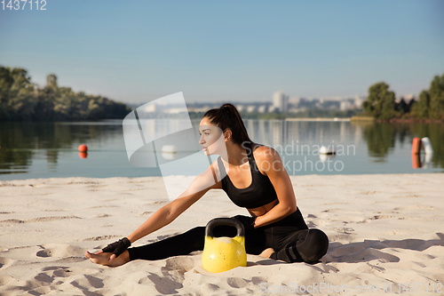 Image of Young healthy female athlete doing workout at the beach
