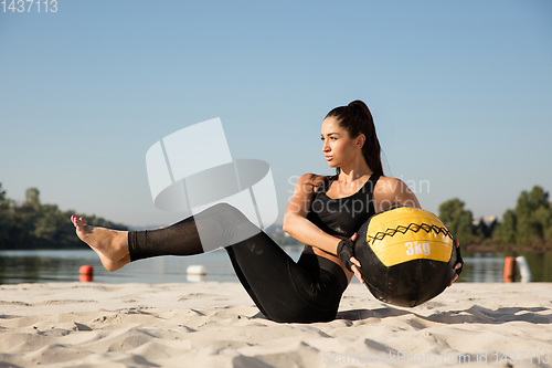 Image of Young healthy female athlete doing workout at the beach