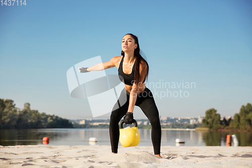 Image of Young healthy female athlete doing workout at the beach