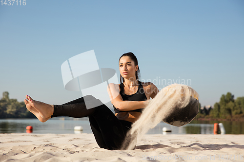 Image of Young healthy female athlete doing workout at the beach