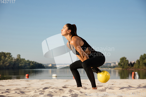 Image of Young healthy female athlete doing workout at the beach
