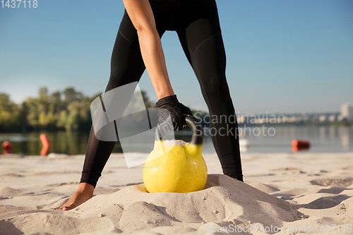 Image of Young healthy female athlete doing workout at the beach
