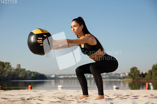 Image of Young healthy female athlete doing workout at the beach