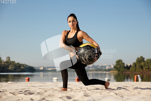 Image of Young healthy female athlete doing workout at the beach