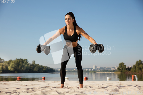 Image of Young healthy female athlete doing workout at the beach