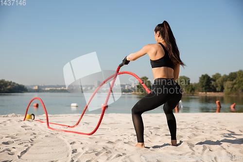 Image of Young healthy female athlete doing workout at the beach