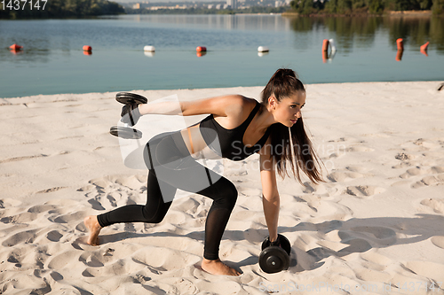 Image of Young healthy female athlete doing workout at the beach
