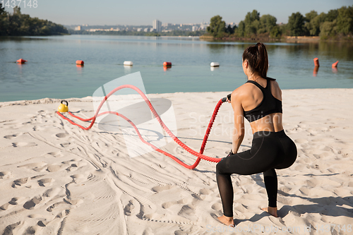 Image of Young healthy female athlete doing workout at the beach