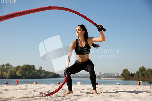 Image of Young healthy female athlete doing workout at the beach