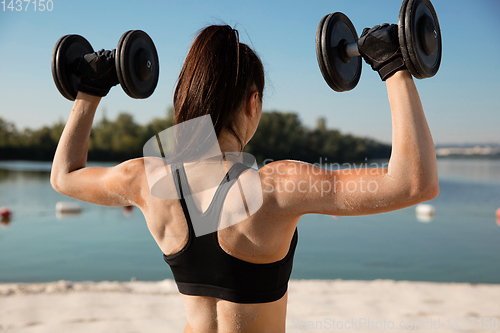 Image of Young healthy female athlete doing workout at the beach