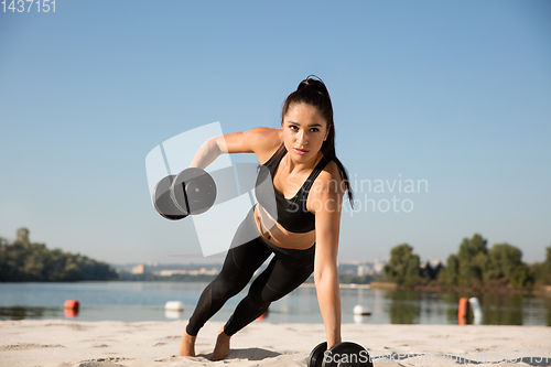 Image of Young healthy female athlete doing workout at the beach